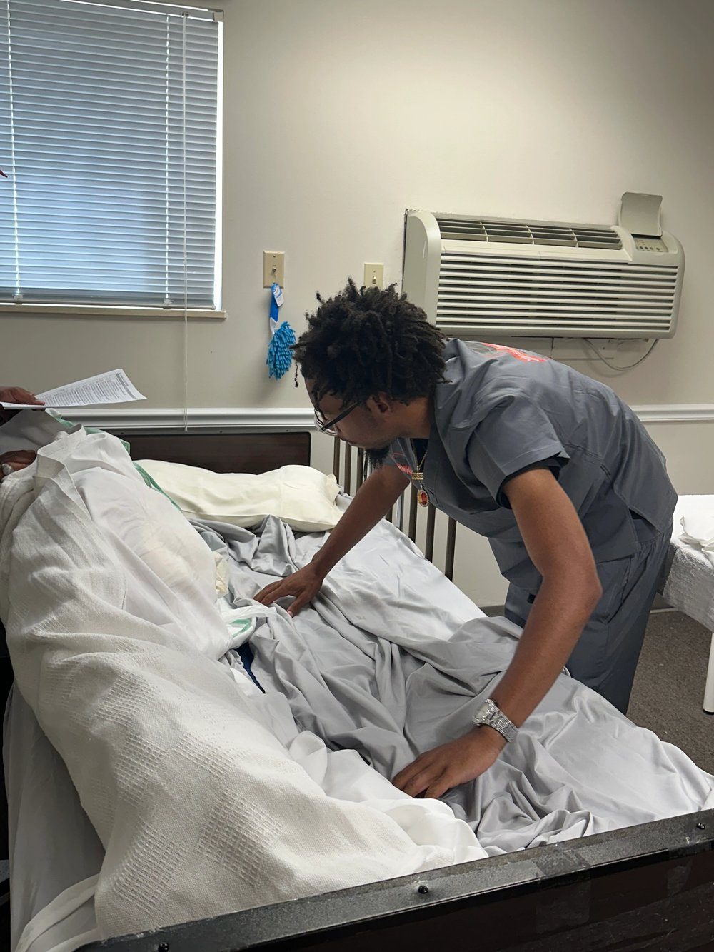 A caregiver checking on a resident in a hospital bed