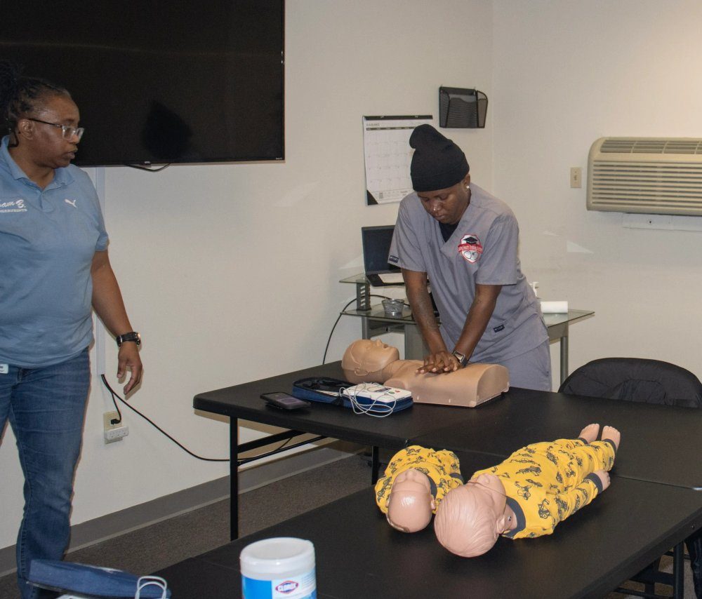 A student practicing CPR on a mannequin while an instructor observes